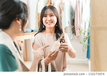 A woman enjoys shopping for interior fragrances at a general store, apparel shop, and clothing store. 110273854