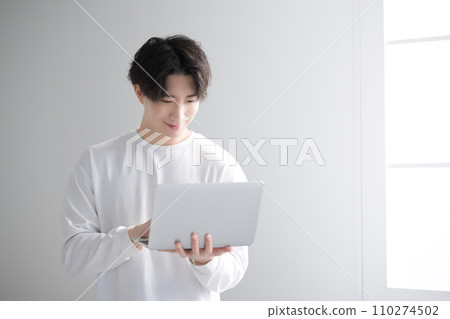 Handsome man using a computer by the window, image of a freelance engineer, designer, etc. 110274502