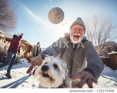 Energetic senior man with a snowball ready to throw, laughing with joy during a snowball fight with friends on a sunny winter day 110276406