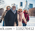 A group of cheerful senior multi-ethnic friends men and women enjoy ice skating in a city park rink with skyscrapers in the background 110276412