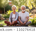 Smiling seniors elderly couple sits cross-legged in sunny garden. Pensioners man and woman wear comfy yoga clothes 110276418