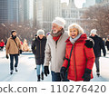 A group of cheerful senior multi-ethnic friends men and women enjoy ice skating in a city park rink with skyscrapers in the background 110276420
