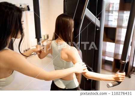 Woman training her back with a pec deck machine 110276431