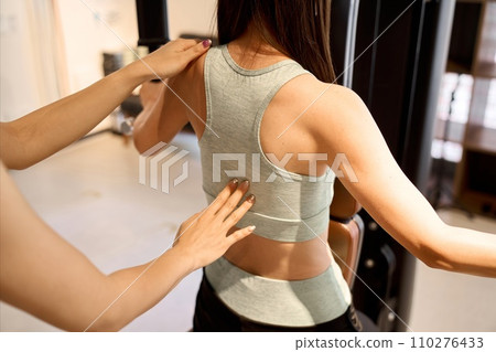 Woman training her back with a pec deck machine Woman training her back with a pec deck machine 110276433