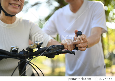 Active senior couple enjoying riding bikes together in nature. Healthy lifestyle concept. Active senior couple enjoying riding bikes together in nature. Healthy lifestyle concept. 110276837
