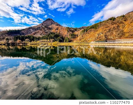 A lake where the mountains of early winter are reflected on the surface of the water. 110277470