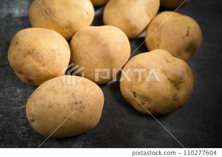fresh potatoes on a black stone background fresh potatoes on a black stone background 110277604