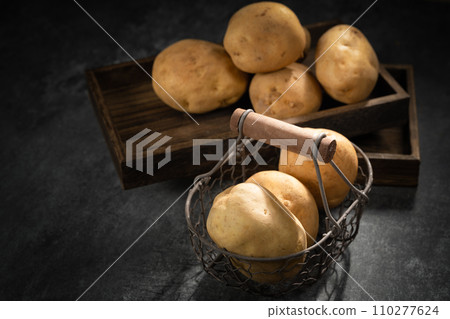 fresh potatoes on a black stone background fresh potatoes on a black stone background 110277624
