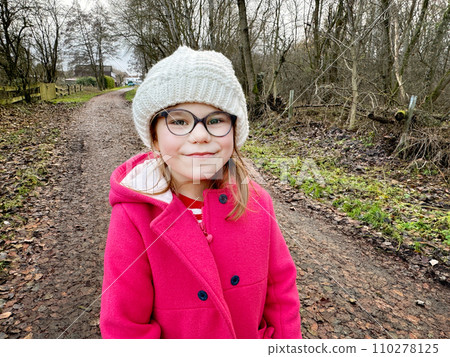 Portrait of a cute school girl with eyeglasses outdoors in park. Happy funny child on autumn, spring or winter day. 110278125
