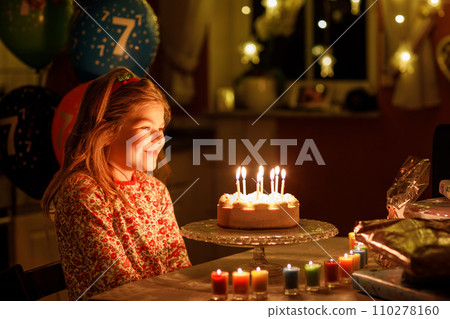 Happy little girl celebrating birthday. Cute smiling child with homemade princess cake, indoor. Happy healthy preschool kid blowing seven candles on cake Happy little girl celebrating birthday. Cute smiling child with homemade princess cake, indoor. Happy healthy preschool kid blowing seven candles on cake 110278160