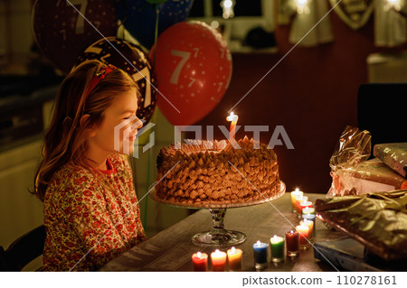 Happy little girl celebrating birthday. Cute smiling child with homemade princess cake, indoor. Happy healthy preschool kid blowing seven candles on cake Happy little girl celebrating birthday. Cute smiling child with homemade princess cake, indoor. Happy healthy preschool kid blowing seven candles on cake 110278161