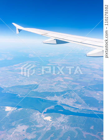Aerial view from airplane window above green ground. View from the airplane window with beautiful clouds at sunrise Aerial view from airplane window above green ground. View from the airplane window with beautiful clouds at sunrise 110278382