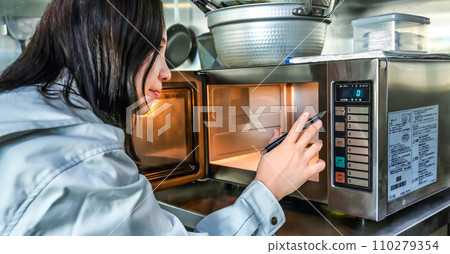 一名年輕女子檢查廚房微波爐的圖像剪輯 110279354