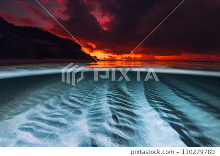 Split view with sunset and underwater sandy sea bottom. Tropical seascape with colorful bright sunset or sunrise, fifty fifty view with artificial light Split view with sunset and underwater sandy sea bottom. Tropical seascape with colorful bright sunset or sunrise, fifty fifty view with artificial light 110279780