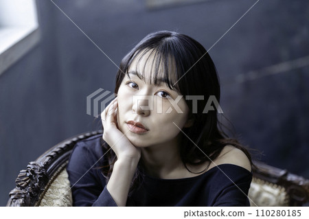 一位穿著黑色洋裝的年輕女子在沙發上放鬆 110280185