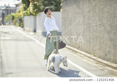 A young woman walking in a residential area with a wire fox terrier 110281406