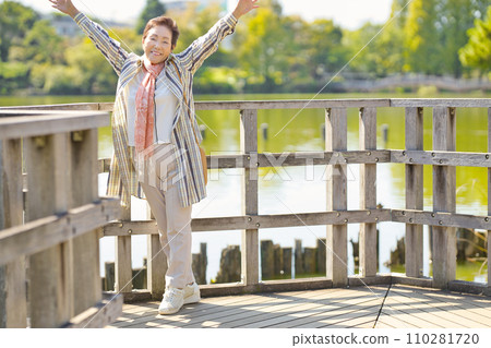 Senior woman walking by the pond Senior woman walking by the pond 110281720
