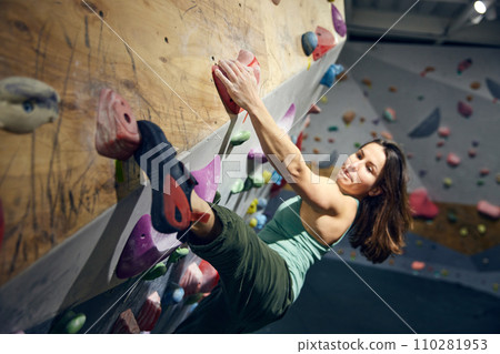 Young athletic woman, training, practicing bouldering activity indoors, climbing wall 110281953
