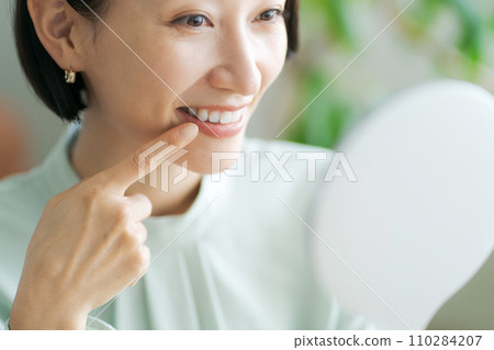 中年婦女對著鏡子檢查牙齒 110284207