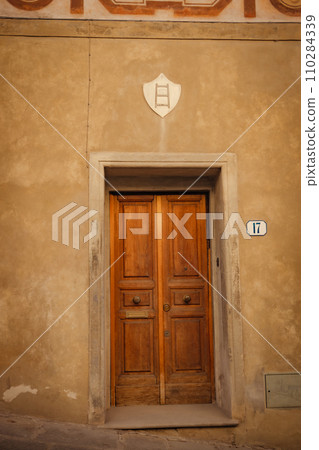 Old wooden italian door in an old building. Historical city elements Classic european architecture of tuscany italy.  110284339