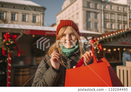 Happy young beautiful woman choosing christmas present and tree at market  110284495