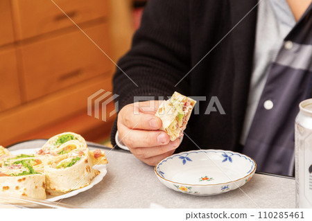 Tortilla in the hands of a man eating Costco's high roll 110285461