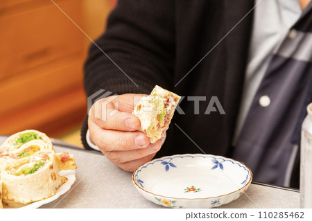 Tortilla in the hands of a man eating Costco's high roll 110285462