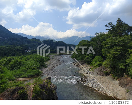 山巒聳立在山澗之外，周圍環繞著夏日的藍天、白雲和綠樹。 110285872