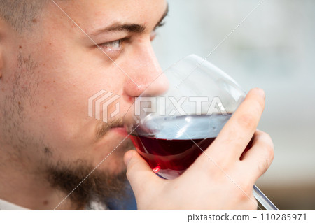 Close-up on the face of a man drinking red wine from a glass. 110285971