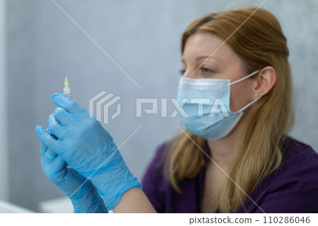 Close-up of the figure of a nurse holding a syringe of medicine in her hands. Close-up of the figure of a nurse holding a syringe of medicine in her hands. 110286046