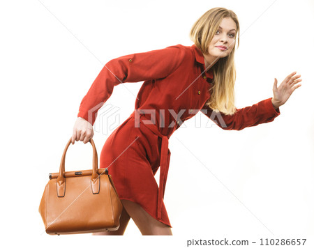 Female wearing red dress holding bag running 110286657