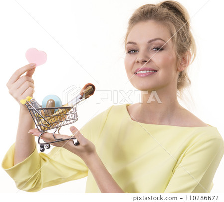 Woman holding shopping cart with make up brushes Woman holding shopping cart with make up brushes 110286672