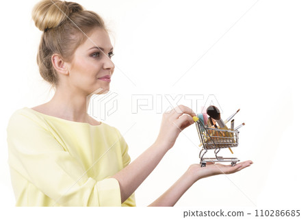 Woman holding shopping cart with make up brushes Woman holding shopping cart with make up brushes 110286685