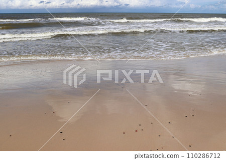 Blue sky and white clouds reflected in wet beach sand 110286712