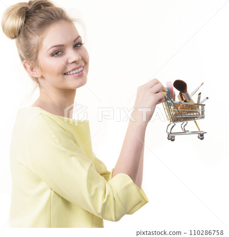 Woman holding shopping cart with make up brushes Woman holding shopping cart with make up brushes 110286758