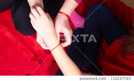 Mother tiying red ribbon for her daughter on her first period. Menarche. First period party Mother tiying red ribbon for her daughter on her first period. Menarche. First period party 110287583