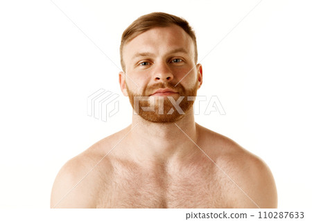 Portrait of young attractive shirtless man with red head and bear looking at camera against white studio background. Concept of beauty. 110287633