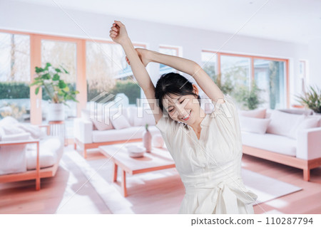 一位年輕女子在明亮的客廳度過時光 一位年輕女子在明亮的客廳度過時光 110287794