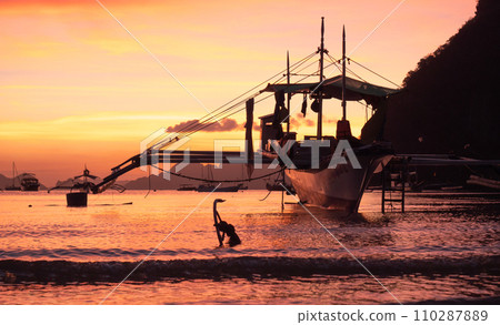 Traditional philippine boat bangka at sunset time. Beautiful sunset with silhouettes of philippine boats in El Nido, Palawan island, Philippines. Orange sky sunset paradise beach. Traditional philippine boat bangka at sunset time. Beautiful sunset with silhouettes of philippine boats in El Nido, Palawan island, Philippines. Orange sky sunset paradise beach. 110287889