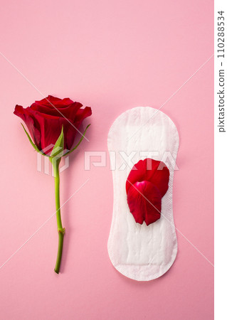 Feminine hygiene pad with red glitter and rose flower. First menstrual period concept on pink background Feminine hygiene pad with red glitter and rose flower. First menstrual period concept on pink background 110288534