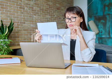 Serious mature businesswoman reading official letter, sitting in office 110289014