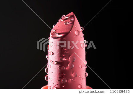 Red lipstick with water drops on a dark background. Red lipstick with water drops on a dark background. 110289425