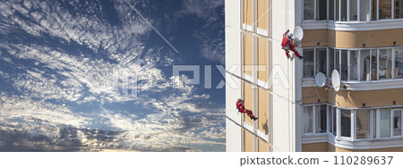 Repair work at height (sealing seams in a panel house), against the sky with clouds. Worker insulates the seams of the facade of an old residential building. Maintenance of residential buildings Repair work at height (sealing seams in a panel house), against the sky with clouds. Worker insulates the seams of the facade of an old residential building. Maintenance of residential buildings 110289637