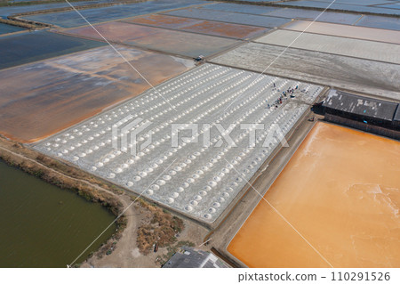Aerial top view of farmers making heaps of raw sea salt piles with sea. Farm field outdoor. Nature material in traditional salt industry in Thailand. Asia culture. Agriculture lifestyle people 110291526