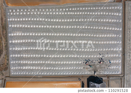 Aerial top view of farmers making heaps of raw sea salt piles with sea. Farm field outdoor. Nature material in traditional salt industry in Thailand. Asia culture. Agriculture lifestyle people 110291528