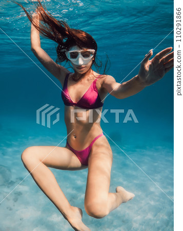 Young woman in bikini swimming underwater in blue ocean. 110291866