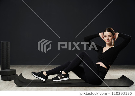 Fit young woman in sportswear working on core, during exercise session on floor of gym. Side view of caucasian sportswoman keeping hands behind head, doing abdominal twist for core. Sport concept. Fit young woman in sportswear working on core, during exercise session on floor of gym. Side view of caucasian sportswoman keeping hands behind head, doing abdominal twist for core. Sport concept. 110293150