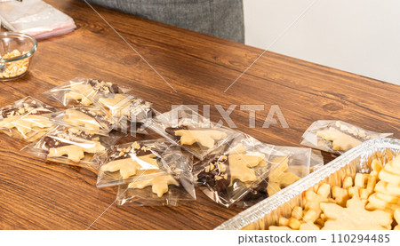 Carefully packaging Christmas cutout cookies, half-dipped in chocolate and presented in clear cellophane wrapping, perfect for festive gifting. Carefully packaging Christmas cutout cookies, half-dipped in chocolate and presented in clear cellophane wrapping, perfect for festive gifting. 110294485