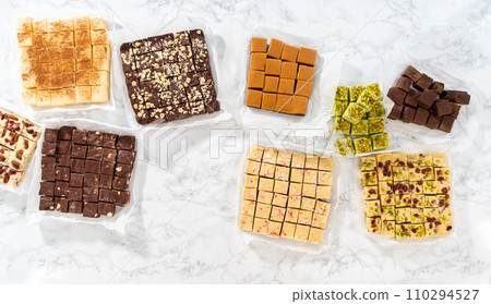 Flat lay. Packaging a homemade variety of fudge for Christmas food gifts into tin boxes. Flat lay. Packaging a homemade variety of fudge for Christmas food gifts into tin boxes. 110294527