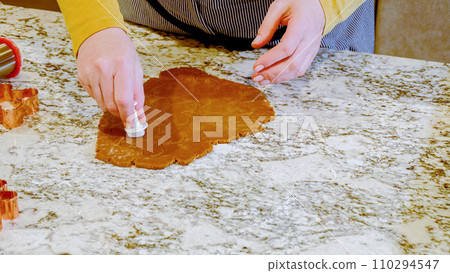 Using various festive cookie cutters, we're cutting out charming gingerbread cookies from the rolled dough on the sleek marble counter, bringing holiday cheer to the modern kitchen. Using various festive cookie cutters, we're cutting out charming gingerbread cookies from the rolled dough on the sleek marble counter, bringing holiday cheer to the modern kitchen. 110294547